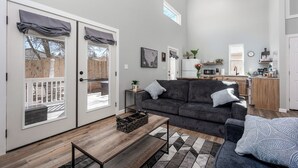 A modern living room with a grey sofa, a wooden coffee table, and a patterned rug. - Hot Tub / Near Downtown / A/C / Couples Retreat (Colorado Springs)