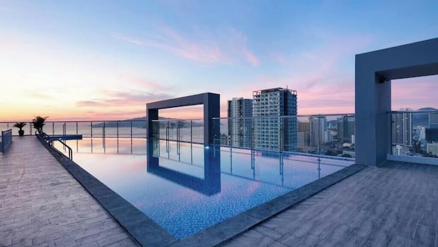 Una piscina en la azotea con vistas a la ciudad al atardecer.