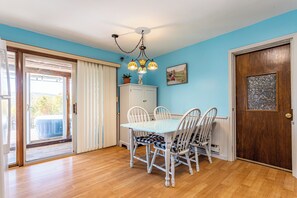 Un comedor con una mesa y sillas, un armario, una puerta y una ventana con cortinas.