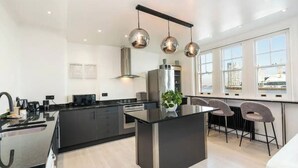 A modern kitchen with a central island, stainless steel appliances, and pendant lighting. - 3 Bdm Flat w/ HotTub and RoofTop (Greater London)