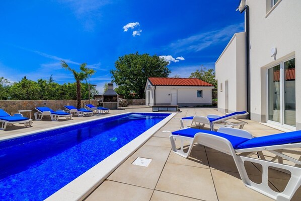 Relax by the pool surrounded by comfortable lounge chairs and lush greenery.