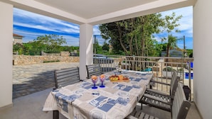 A covered outdoor dining area with a table set for two, featuring a newspaper tablecloth and a variety of food items. - Large pool with salt electrolysis not far from the healing mud bay (Kras-Dobrinj)