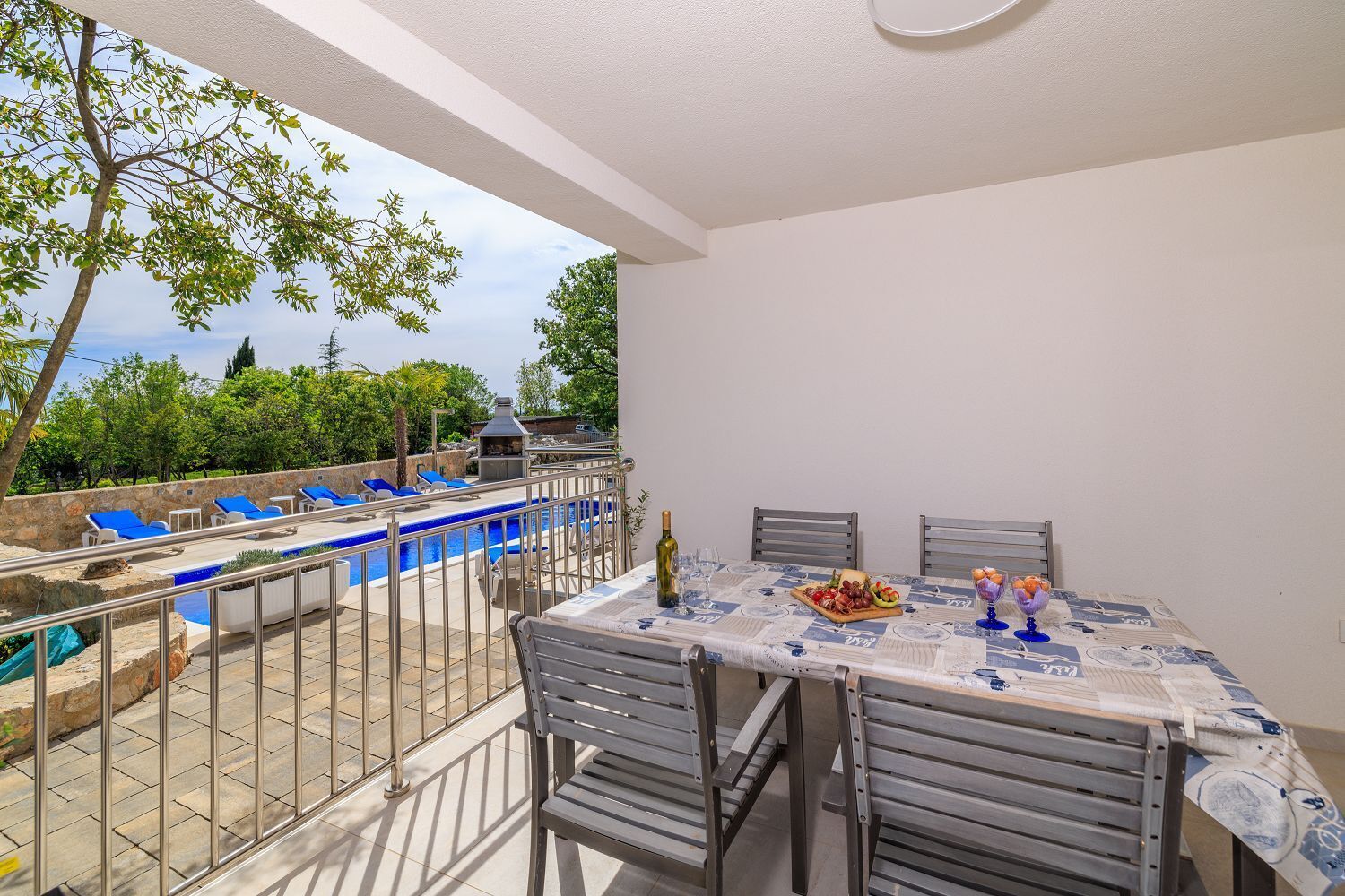 A terrace with a pool, outdoor seating, and a table set for dining.