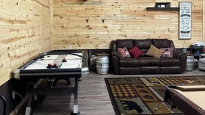 Une pièce chaleureuse aux murs en bois, avec une table de billard, un canapé en cuir et un tapis décoratif.