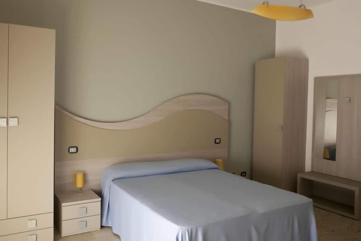 A bedroom with a bed, bedside tables, a wardrobe, and a mirror.