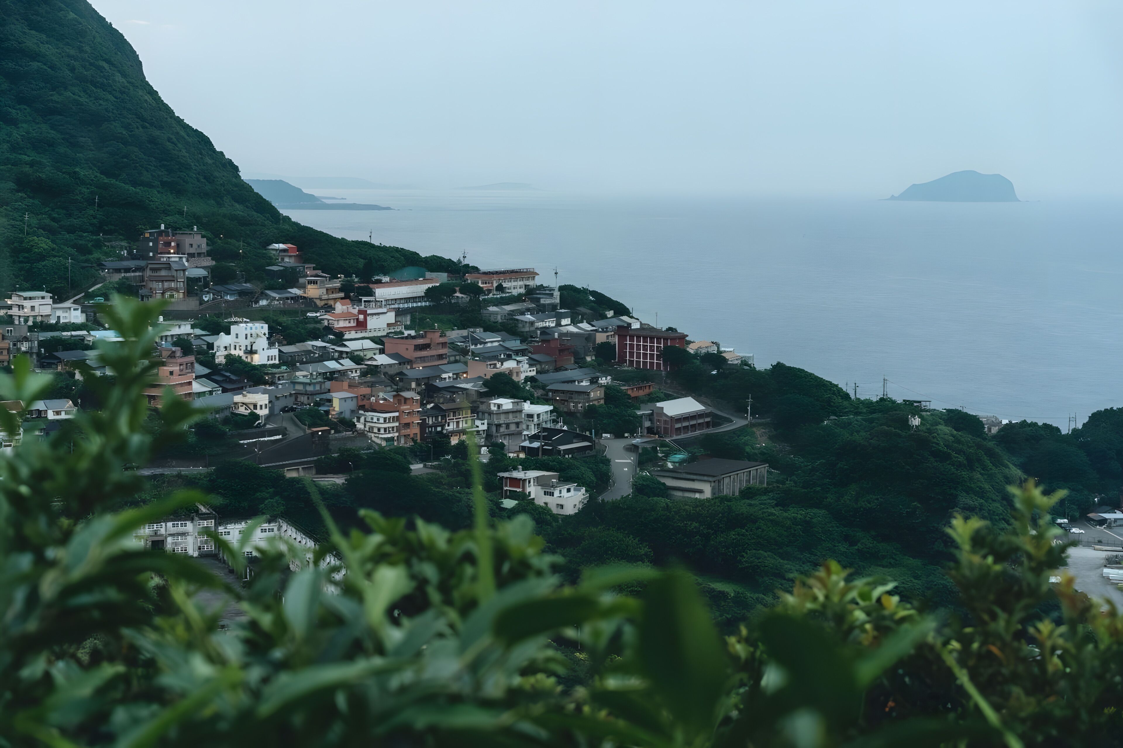 A coastal town with buildings on a hillside, overlooking the sea.
