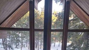 A cozy room with a large window, a fireplace, and a chair. - Bear Valley Alpine Cabin-3bdrm2bth (Bear Valley)