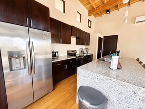 Una cocina moderna con electrodomésticos de acero inoxidable, gabinetes de madera oscura y encimera de granito.