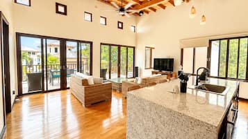 A spacious living area with a kitchen island, sliding glass doors to a balcony, and a ceiling fan.