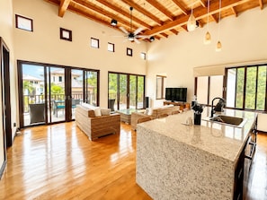 A spacious living area with a kitchen island, sliding glass doors to a balcony, and a ceiling fan. - Living Waters Casita  Private Pool, Camp Bay (Camp Bay)