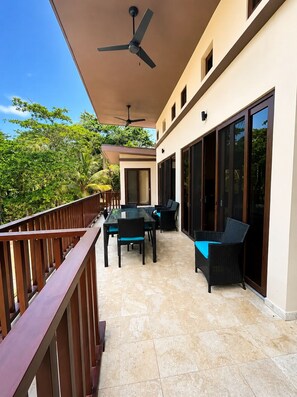 A balcony with a table and chairs, a ceiling fan, and a view of greenery. - Living Waters Casita  Private Pool, Camp Bay (Camp Bay)