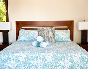A bed with a floral-patterned bedspread, two pillows, and a nightstand with a lamp. - Living Waters Casita  Private Pool, Camp Bay (Camp Bay)