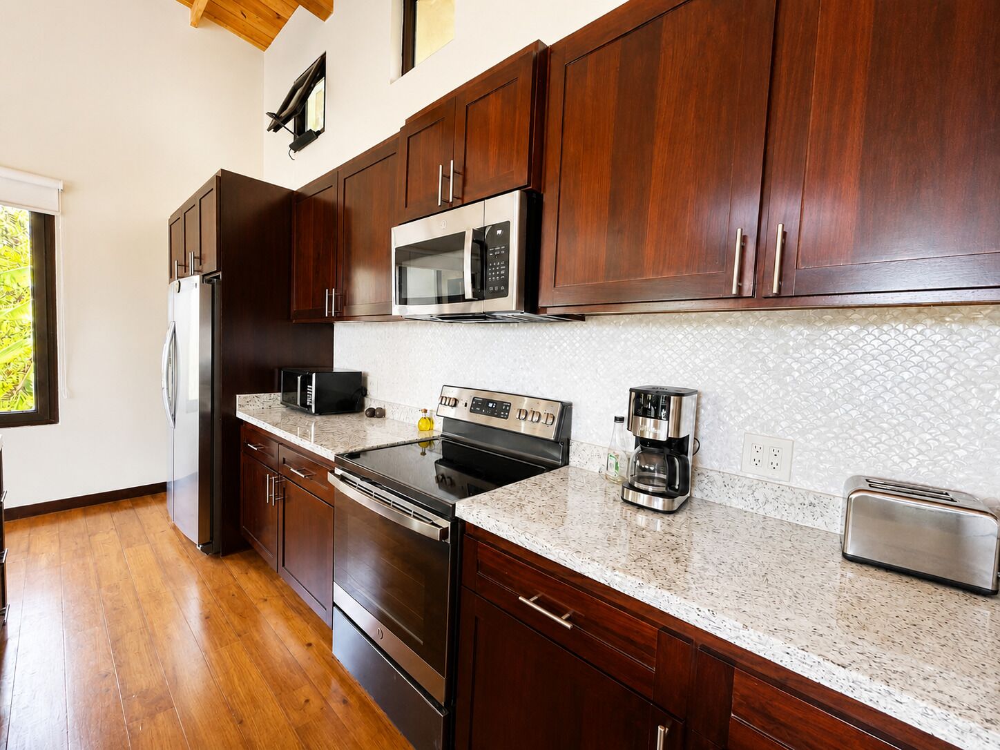 A modern kitchen with dark wood cabinets, stainless steel appliances, and a granite countertop.