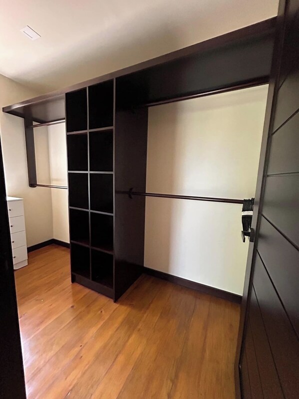 A room with a wooden floor, a white wardrobe, and a black shelving unit. - Living Waters Casita  Private Pool, Camp Bay (Camp Bay)