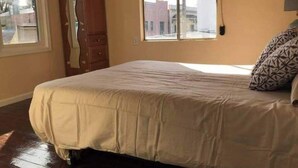 Un dormitorio con cama, armario, ventana y aire acondicionado instalado en la pared.