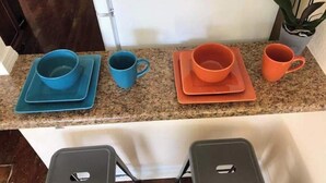 Una encimera de cocina con vajilla y tazas en azul y naranja.