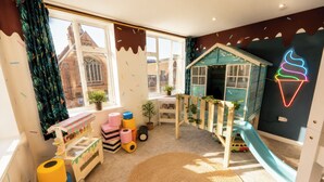 A child's playroom with a slide, playhouse, and various toys. - 3BR Westbourne Delight - Near Beach & Bournemouth! (Bournemouth)