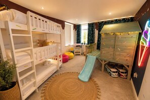Une salle de jeux pour enfants avec des lits superposés, un toboggan et une cabane.