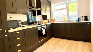 A modern kitchen with dark cabinetry, a built-in oven, a microwave, and a window providing natural light.