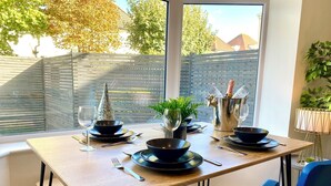 A dining table set with black bowls, wine glasses, and cutlery.
