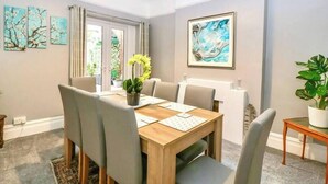 Un comedor con una mesa de madera, seis sillas y una planta en maceta.