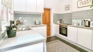 Una cocina moderna con armarios blancos, baldosas grises y una alfombra estampada.