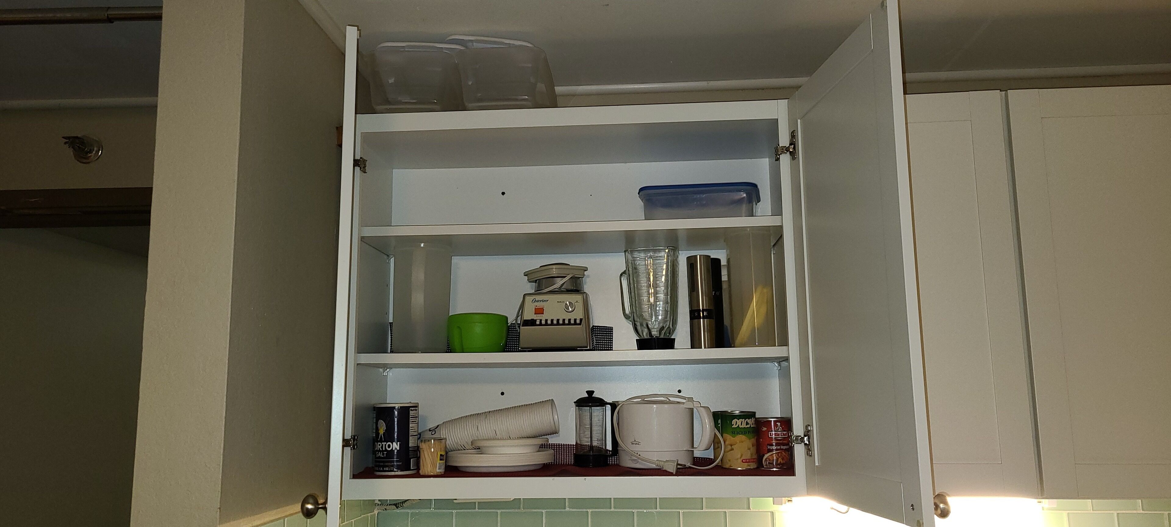 A kitchen cabinet with shelves containing various kitchen items like containers, a blender, a kettle, and a coffee maker.