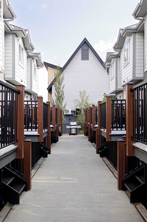 A corridor leading to a building with a gabled roof and a small window. - Summit Rails | 3BR Loft | Unique Canmore Character | Walk to Everything | Sleeps 6 (Canmore)