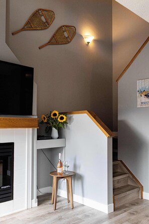 A staircase with wooden handrails, a wall-mounted light fixture, and a framed picture. - Summit Rails | 3BR Loft | Unique Canmore Character | Walk to Everything | Sleeps 6 (Canmore)
