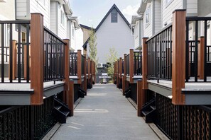 A narrow pathway flanked by wooden fences and white buildings with black railings.