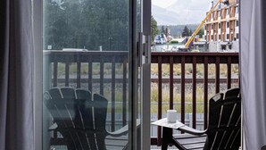 A room with a sliding glass door leading to an outdoor deck with chairs and a table. - Summit Rails | 3BR Loft | Unique Canmore Character | Walk to Everything | Sleeps 6 (Canmore)