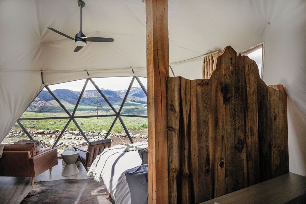 A tent with a bed, a table, and a chair inside.