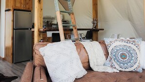 A cozy interior with a wooden ladder, a kitchenette, and a brown leather couch with decorative pillows. - Cody Peak Dome, Stunning Views! Near Cody, WY and Yellowstone National Park (Cody)