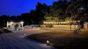 Un espace extérieur bien éclairé, doté d’une piscine, de sièges et de guirlandes lumineuses.