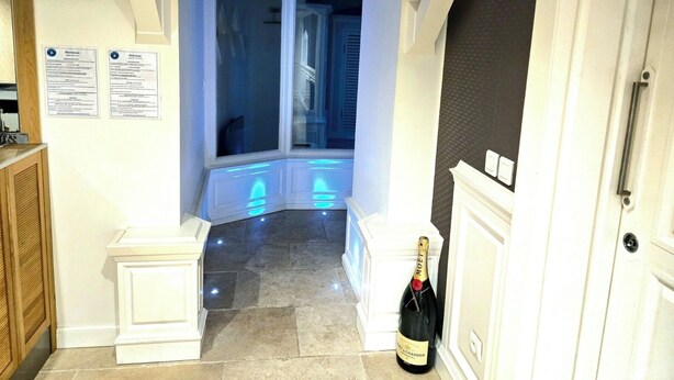 Een hotelentree met een erker, een fles champagne en welkomstborden.