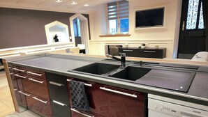 Een moderne keuken met een centraal eiland, een dubbele spoelbak en een geïntegreerde vaatwasser.