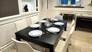 Een eetruimte met een zwarte tafel gedekt voor zes personen, witte stoelen en een raam met uitzicht.