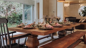 A dining table set with glassware and plates, surrounded by wooden benches and chairs.