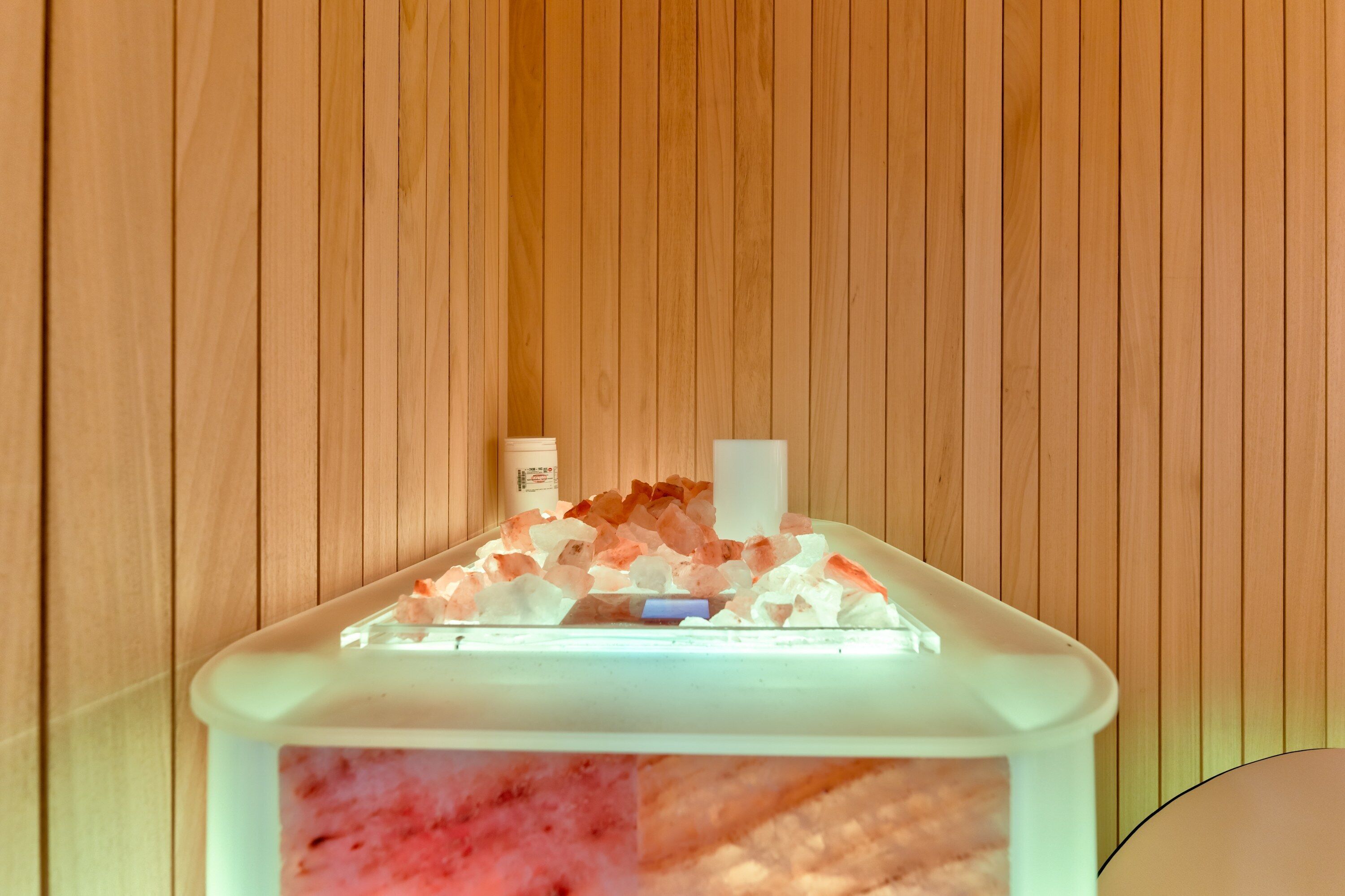 A spa area with a wooden panel wall, a massage table with a white cover, and two bottles of massage oil.