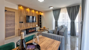 Un salon moderne doté d’un téléviseur à écran plat, de lambris en bois, d’un canapé, d’une table à manger et d’une cheminée.