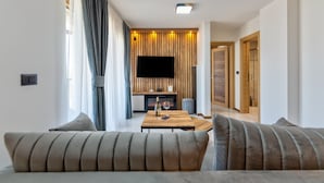 Un salon moderne avec un canapé, une table basse et un téléviseur à écran plat fixé à un mur en bois.