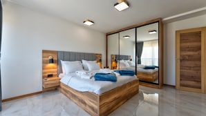 Une chambre à coucher moderne avec un cadre de lit en bois, un grand miroir et des tables de chevet intégrées.