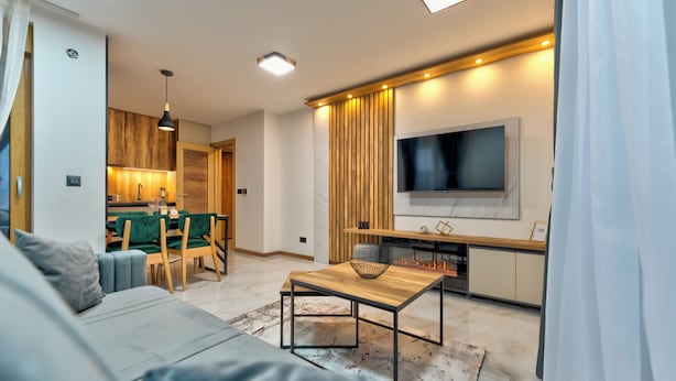 Un salon moderne avec un canapé, une table basse et un téléviseur fixé au mur.