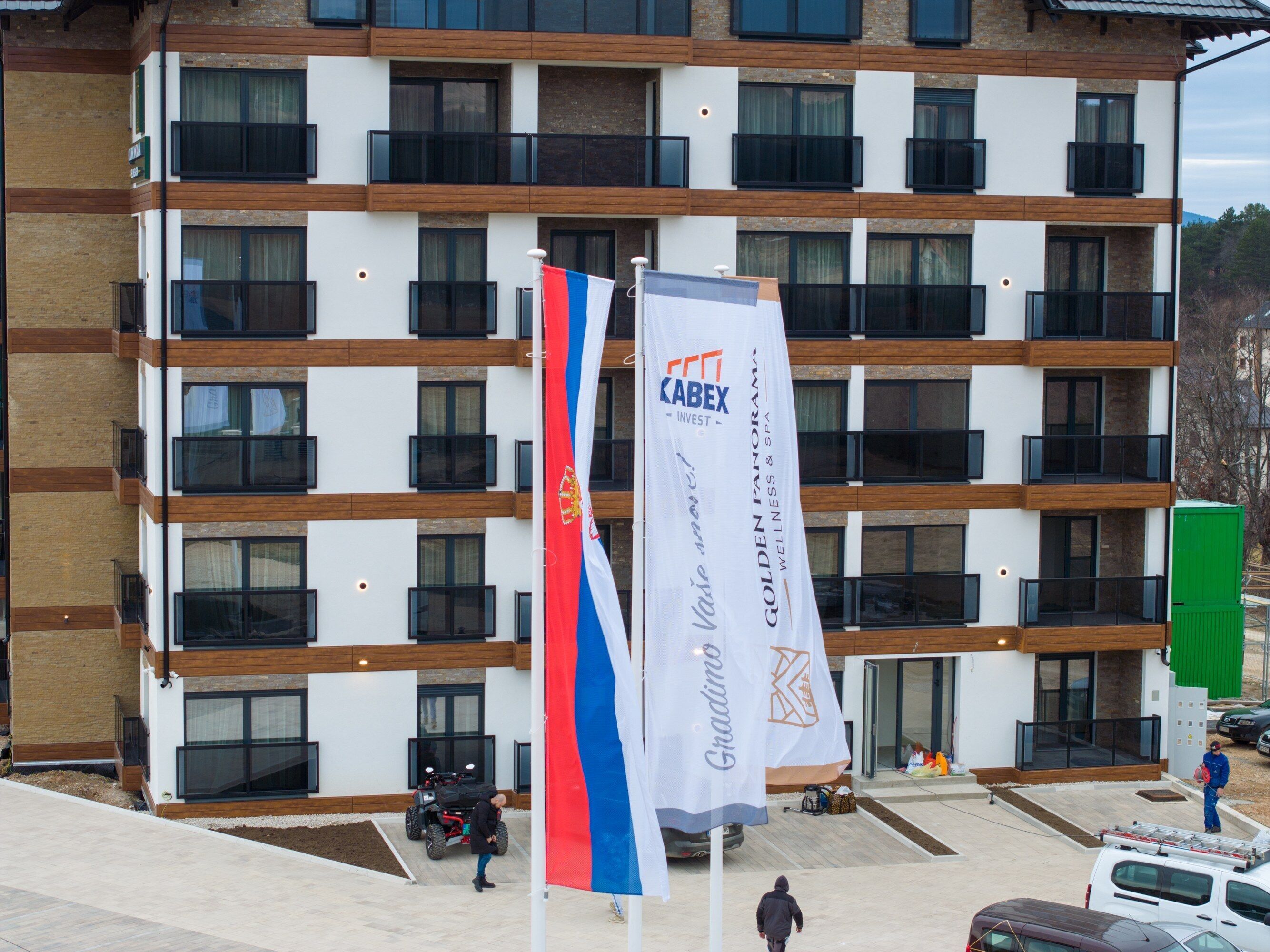 Un edificio de varios pisos con balcones, una bandera y un cartel que dice 'KABEX INVEST'.