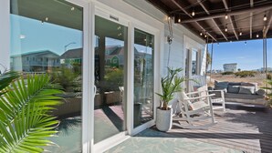 Eine überdachte Terrasse im Freien mit Sitzgelegenheit, einem Blumentopf und Blick auf Häuser im Hintergrund.
