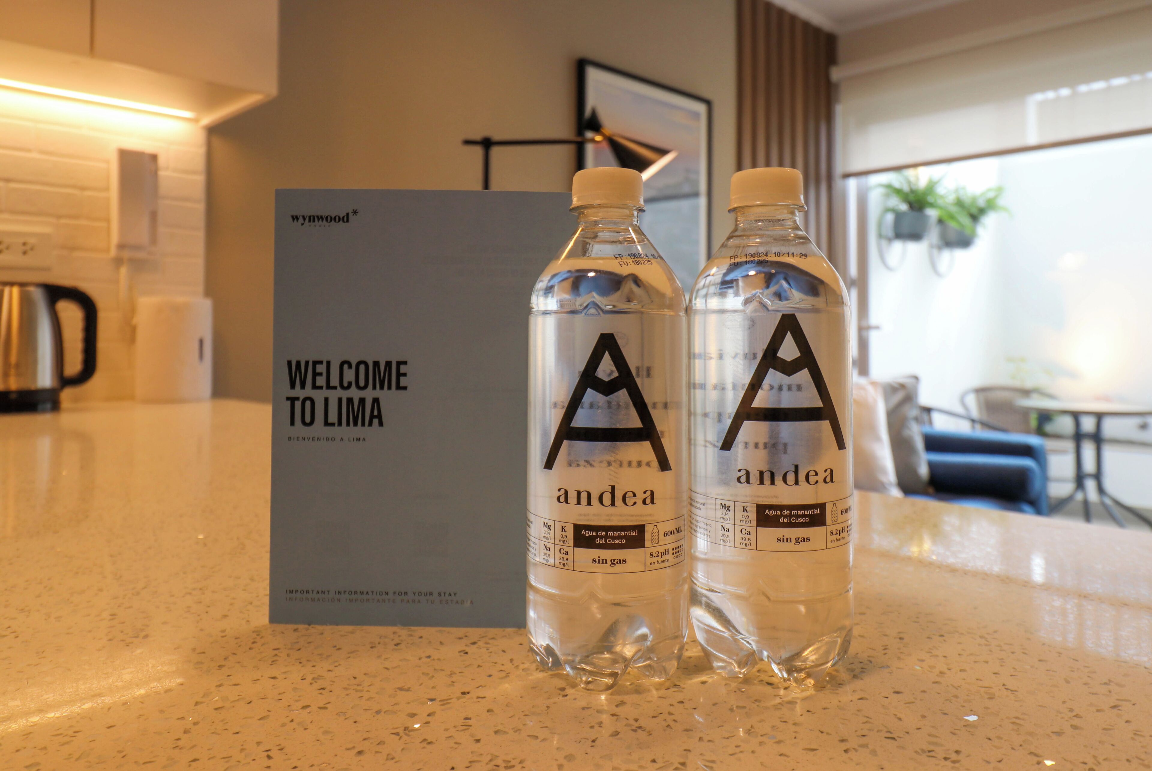 Two water bottles labeled 'andea' on a countertop with a 'WELCOME TO LIMA' sign in the background.