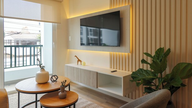A modern living room with a large TV mounted on the wall, a wooden console table, and a potted plant.