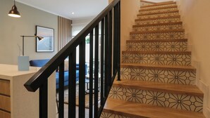 A staircase with a geometric patterned design, a black handrail, and a modern light fixture.