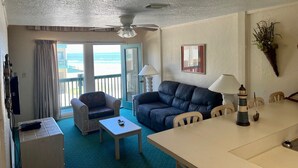 A room with a balcony, a sofa, a table, and a lamp.