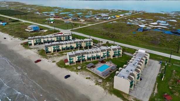 A coastal hotel with multiple-story buildings, a swimming pool, and a beach area.